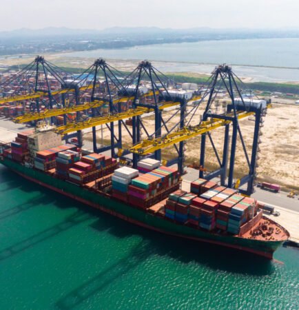 Commercial cargo container vessel facilitating shipping in Oman at port terminal