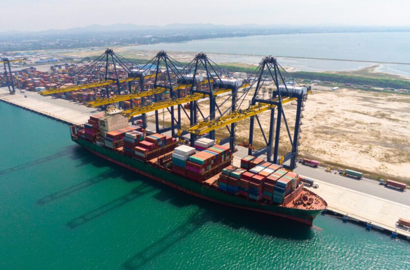 Commercial cargo container vessel facilitating shipping in Oman at port terminal